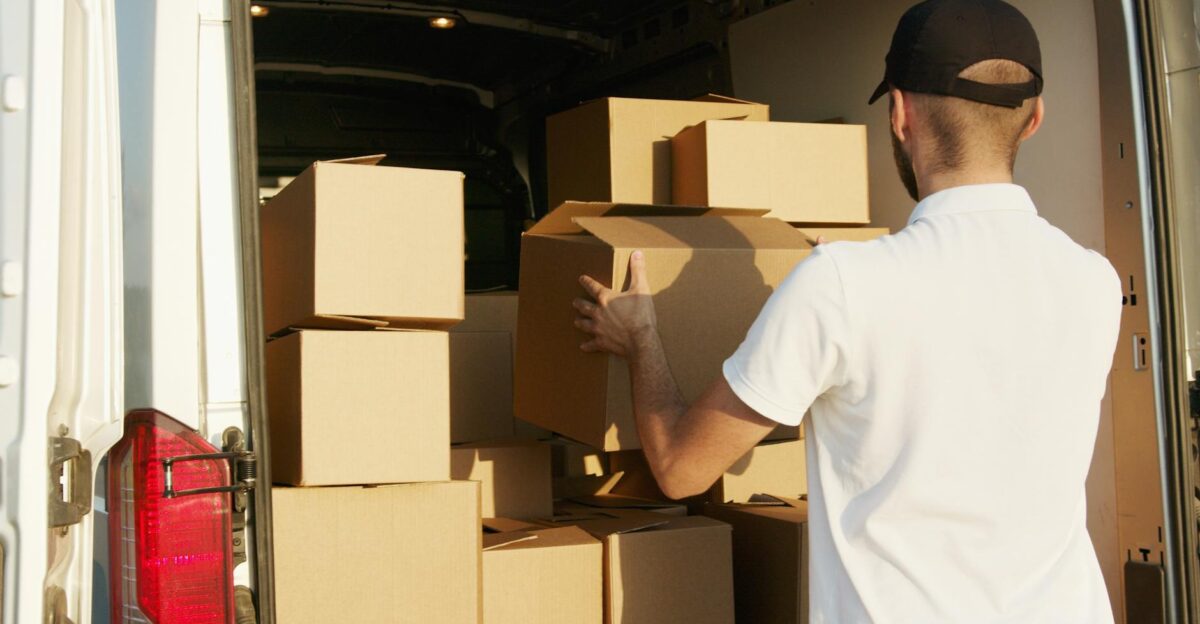 Courier arranging cardboard boxes in a delivery van during daytime