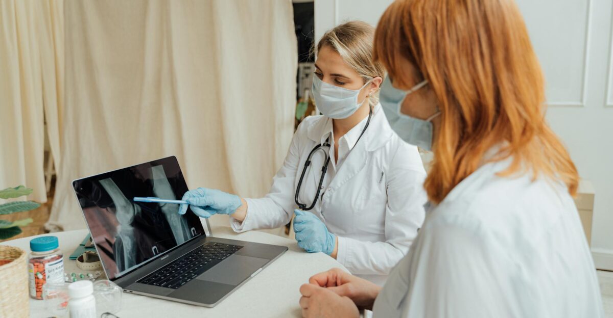 Doctor explains X-ray results to patient using a laptop in a clinic setting