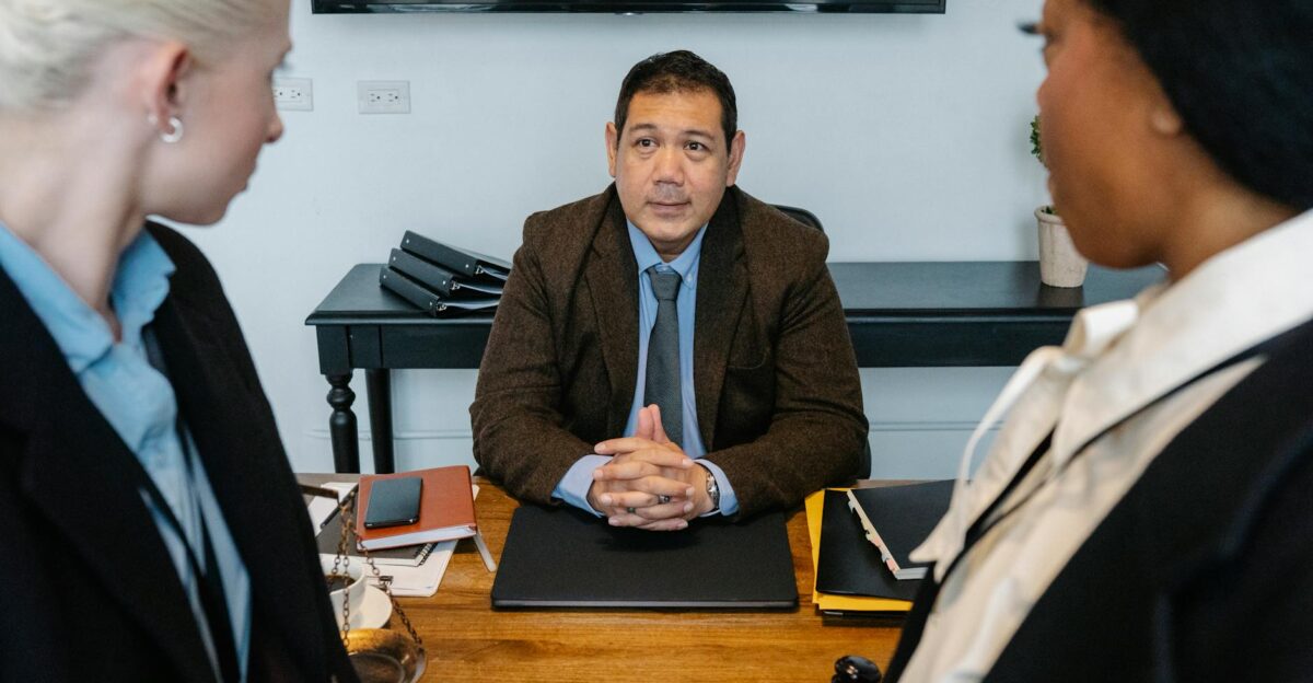Three diverse attorneys in a formal meeting at a law firm office table