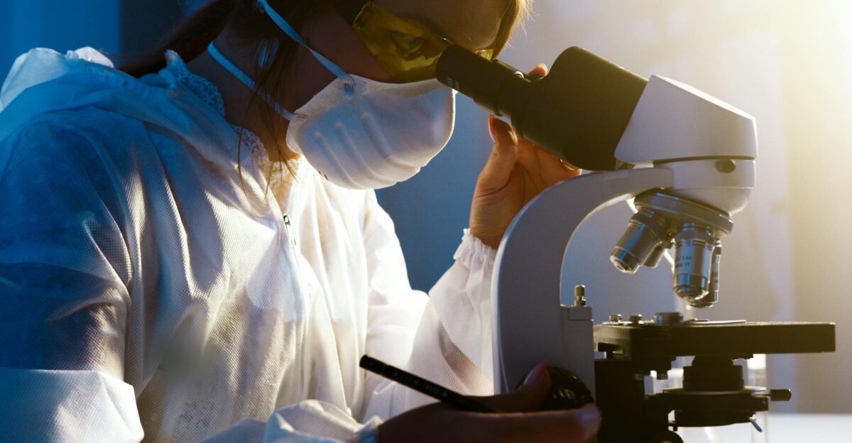 A female scientist uses a microscope in a laboratory focusing intently on her research