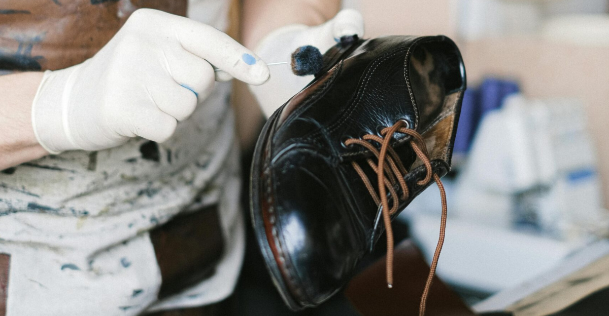Close-up of a craftsman polishing a leather shoe in a workshop, focusing on detail and craftsmanship.