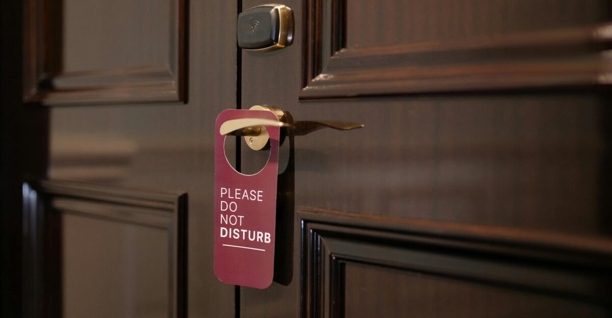 A wooden hotel door with a Please Do Not Disturb sign hanging on the handle
