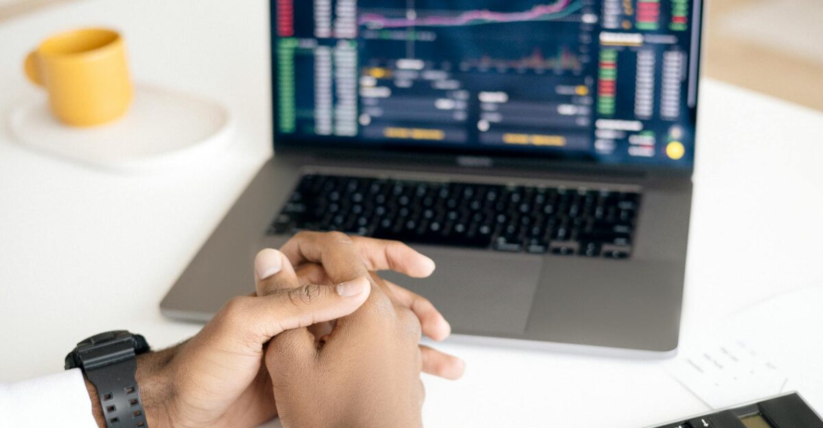 Close-up of a person analyzing stock data on a laptop with graphs and charts visible