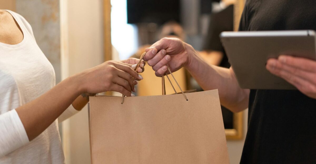 Close-up of hands exchanging a shopping bag indoors symbolizing modern retail and technology
