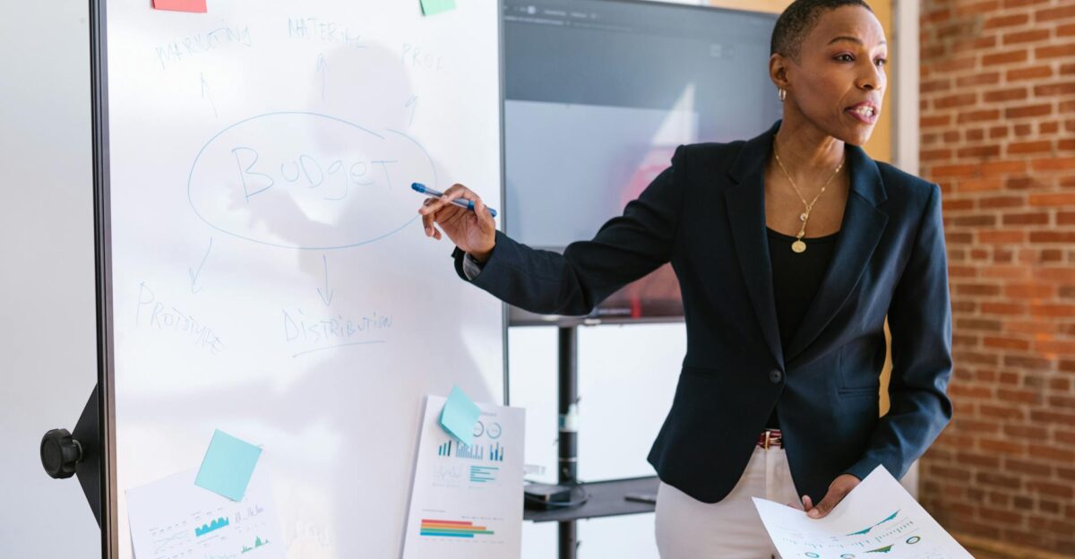 Professional businesswoman explaining budget strategy on a whiteboard during a meeting