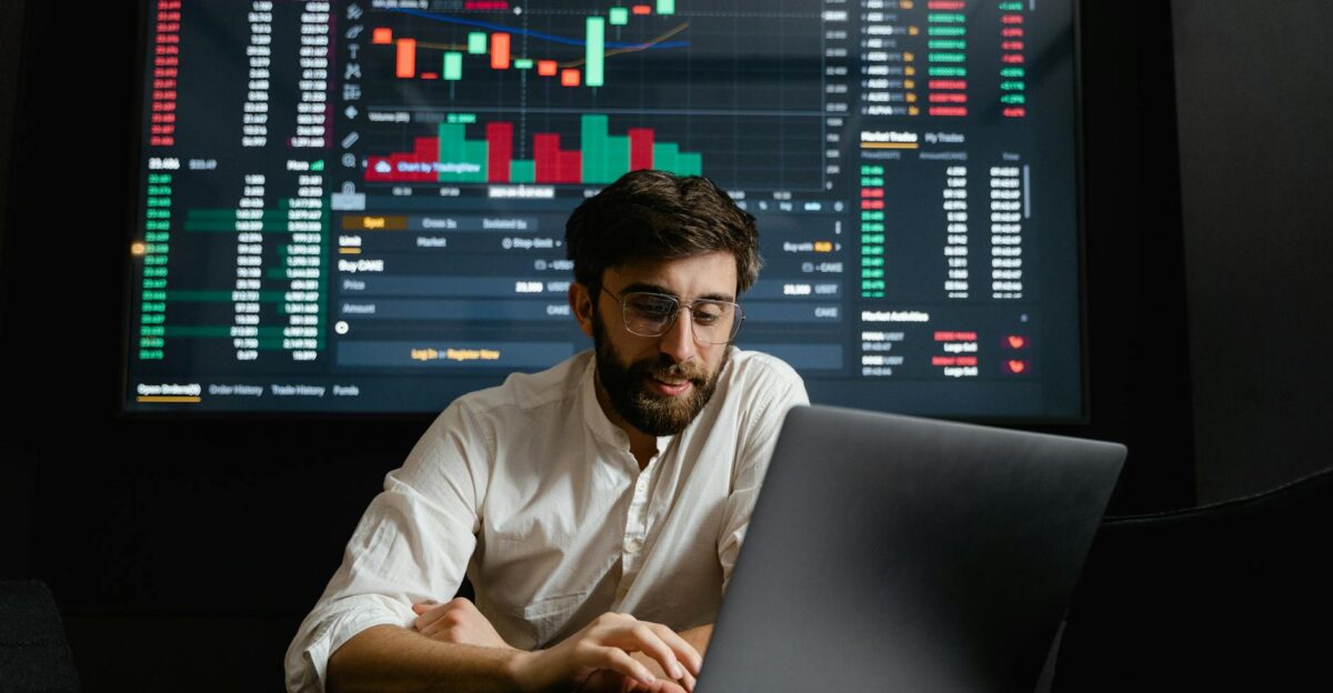 Male analyst studies cryptocurrency trends at a workstation with multiple displays showing market data