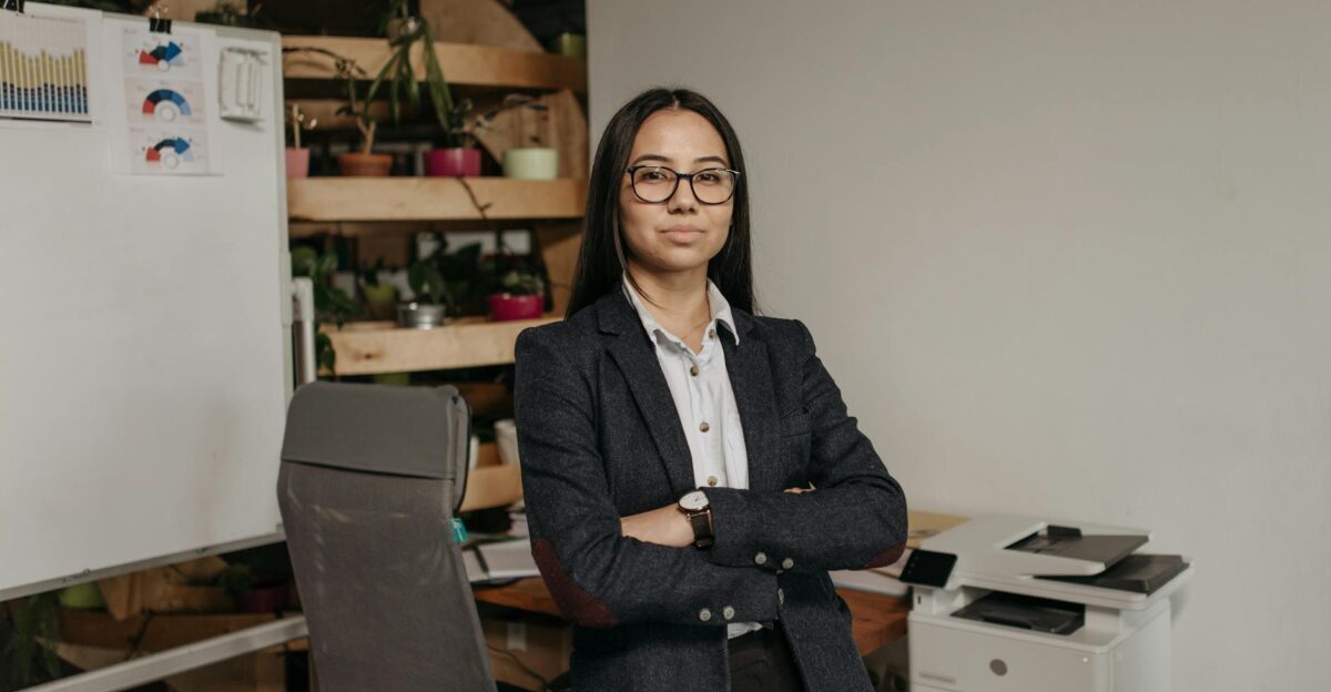 Confident woman in business attire standing in modern office with arms crossed