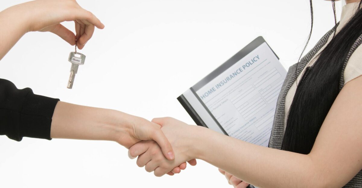 A real estate transaction with a handshake and key exchange highlighting a home insurance document