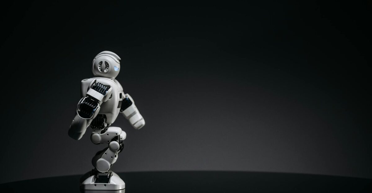 A sleek white toy robot poised elegantly against a dark studio backdrop