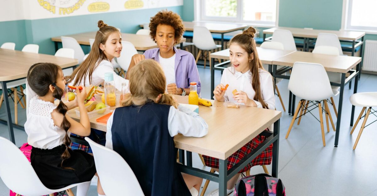 A diverse group of school children enjoying lunch together in a canteen