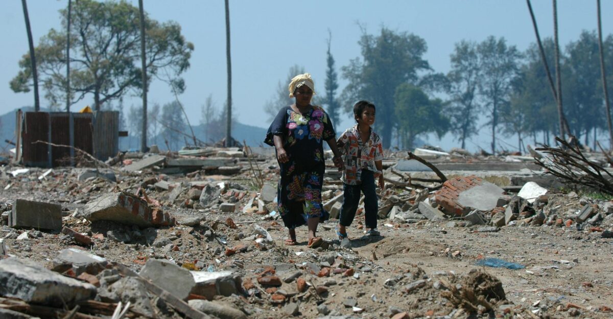 Two people walk through debris in Banda Aceh Indonesia after a devastating tsunami