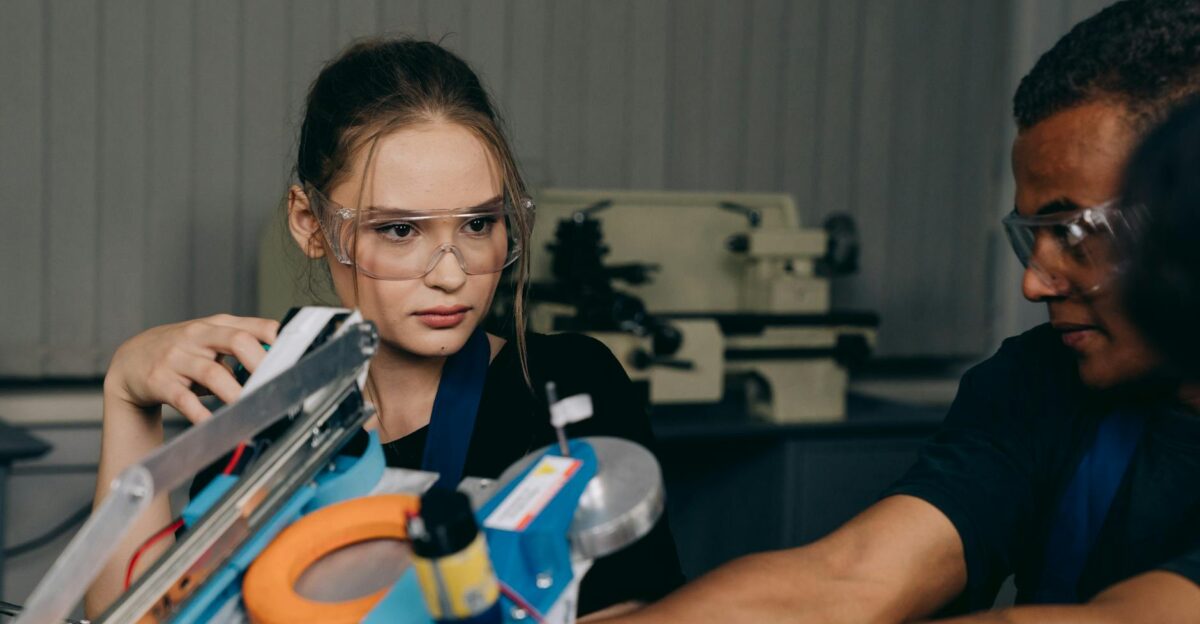 Group of young engineers collaborating on robotic equipment in an indoor industrial setting