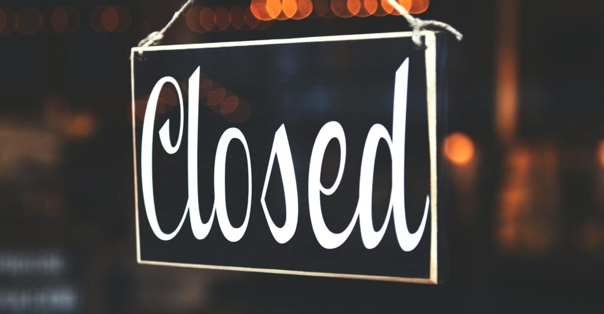 A close-up of a Closed sign hanging against a blurred bokeh background creating a warm inviting atmosphere