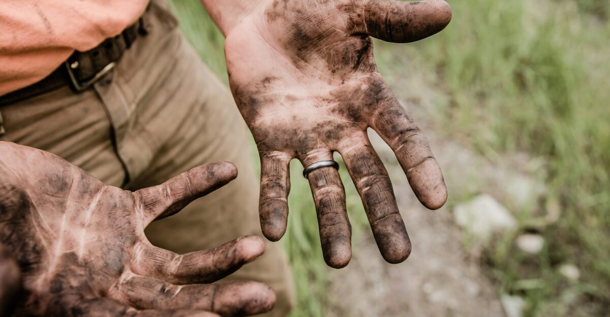 A man with his hands covered with mud