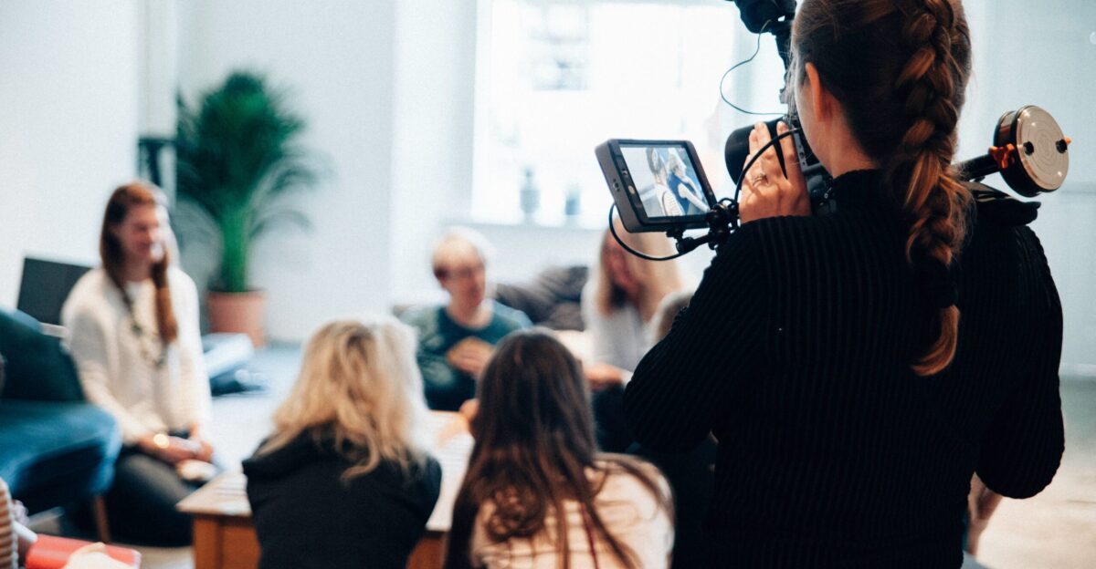 woman holding camera standing near people