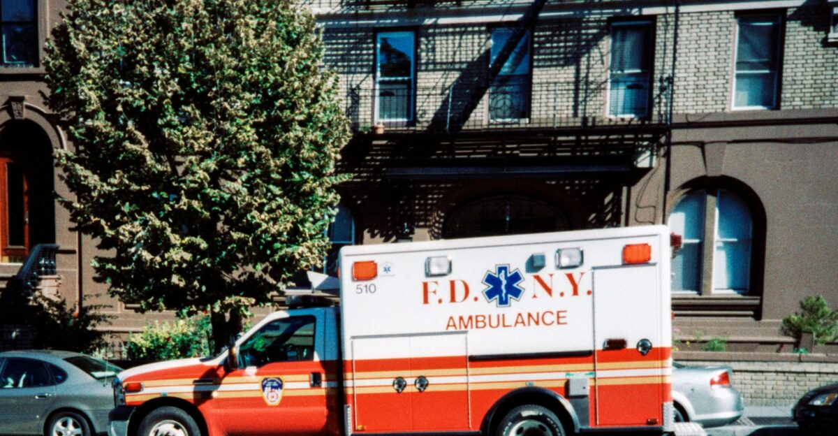 white and red ambulance van parked near green trees during daytime