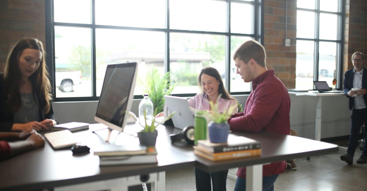 a group of people standing around a table with a laptop