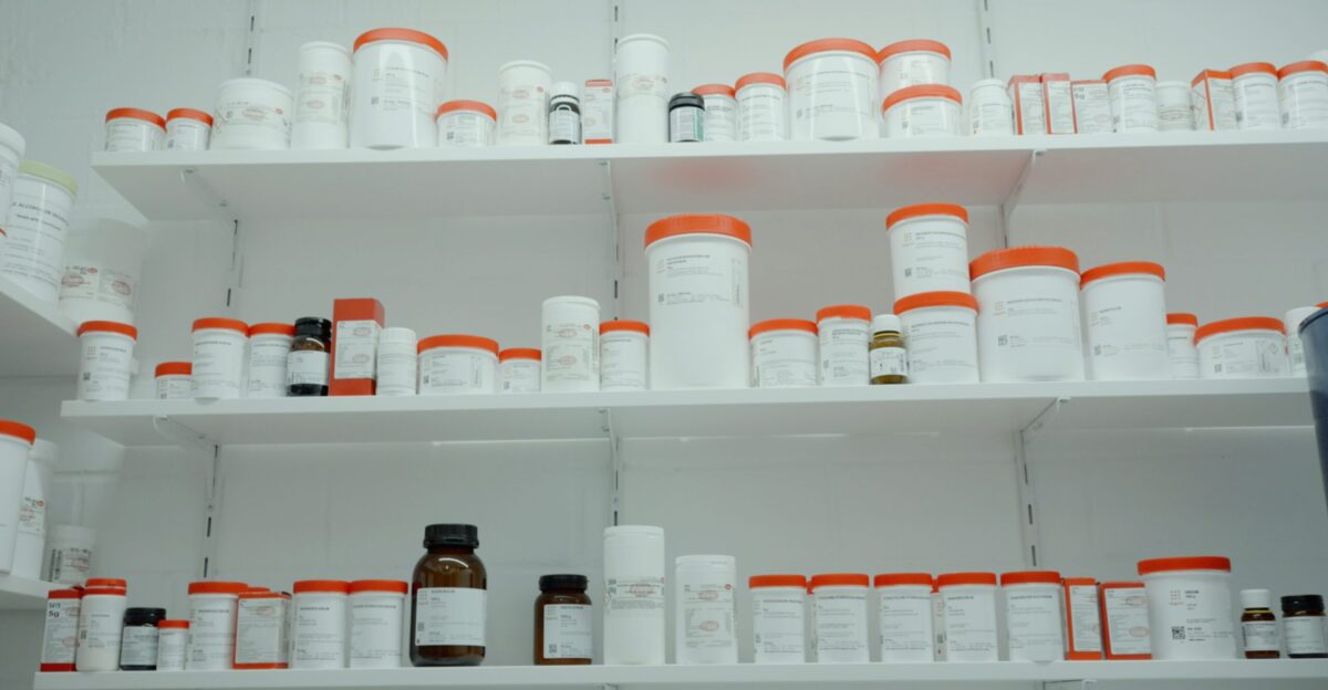 a shelf filled with lots of white and orange medicine bottles