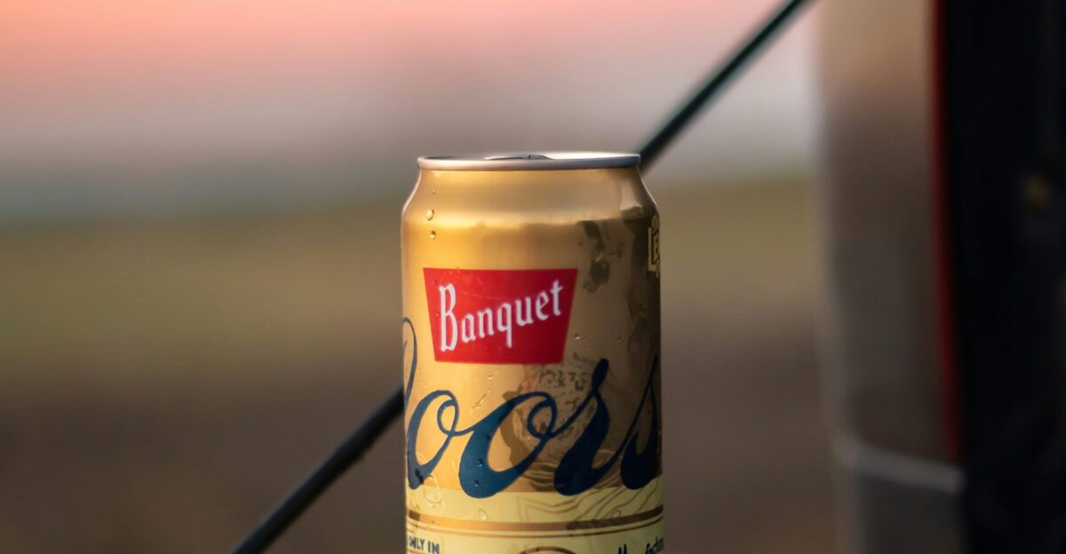 a can of beer sitting on the hood of a car