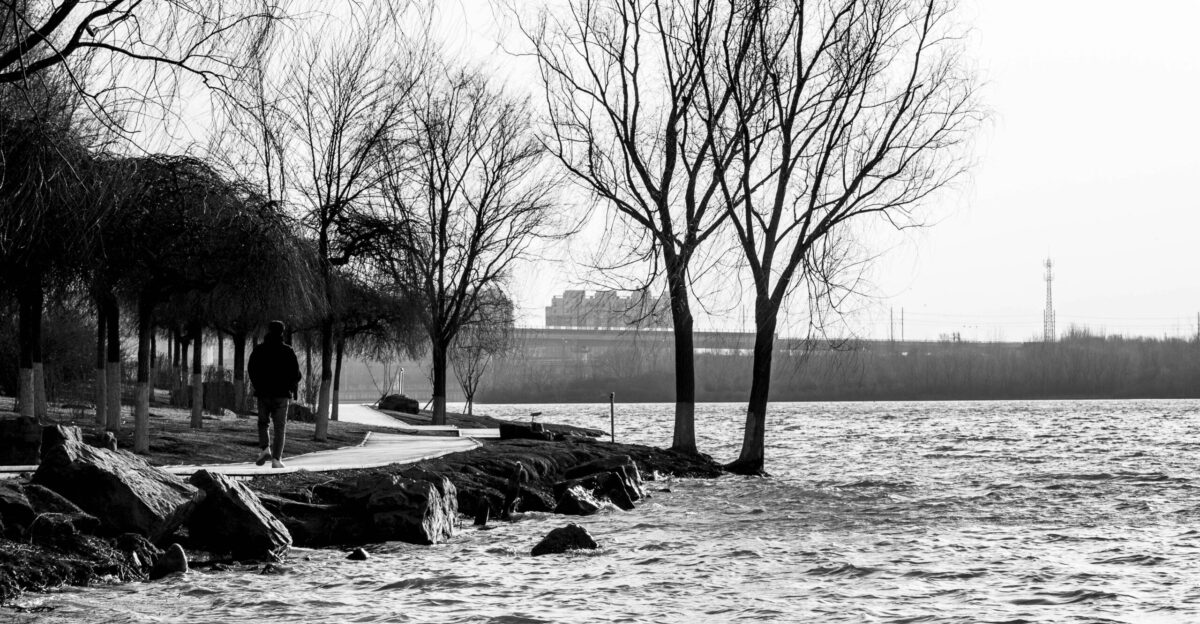 a man walking down a sidewalk next to a body of water