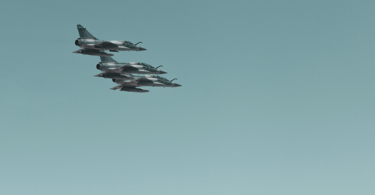 a group of fighter jets flying through a blue sky