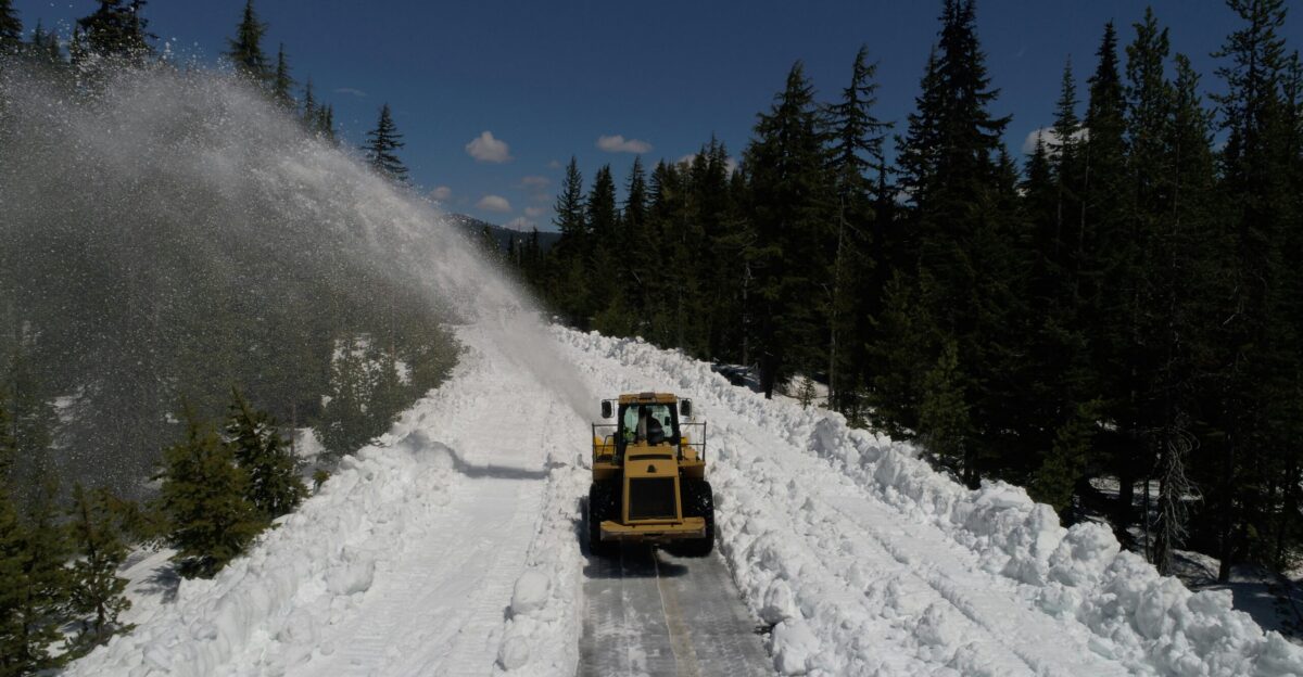 a snow plow driving down a snow covered road