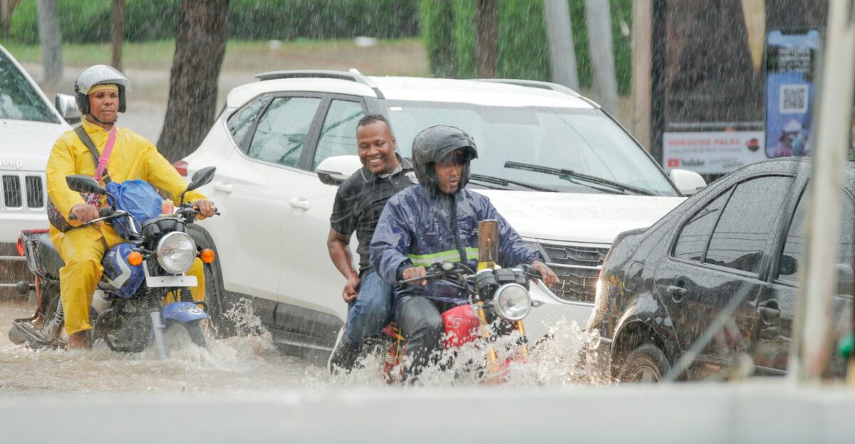 A group of people riding motorcycles through a flooded street