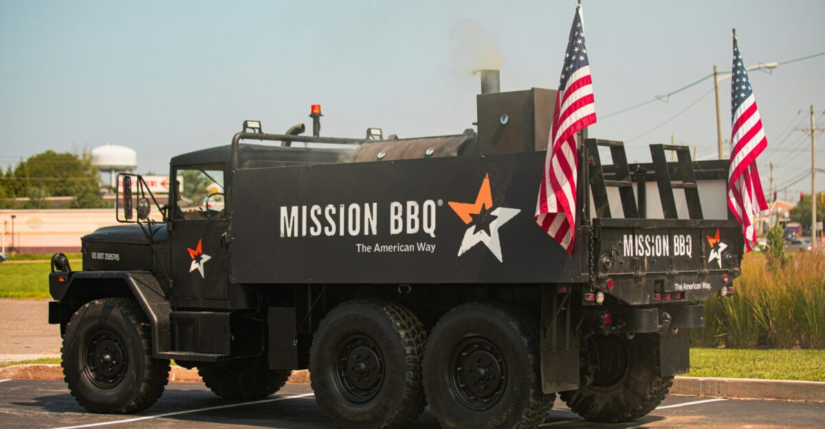 A military truck driving down a street with american flags