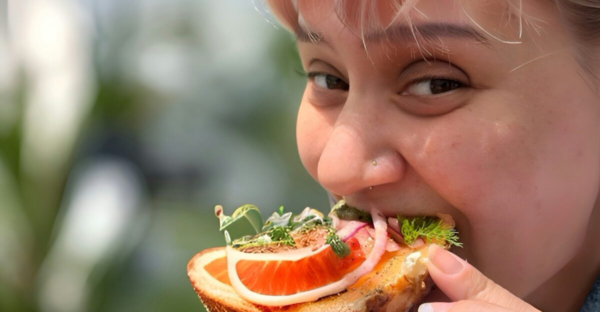 A woman is eating a sandwich with oranges and lettuce
