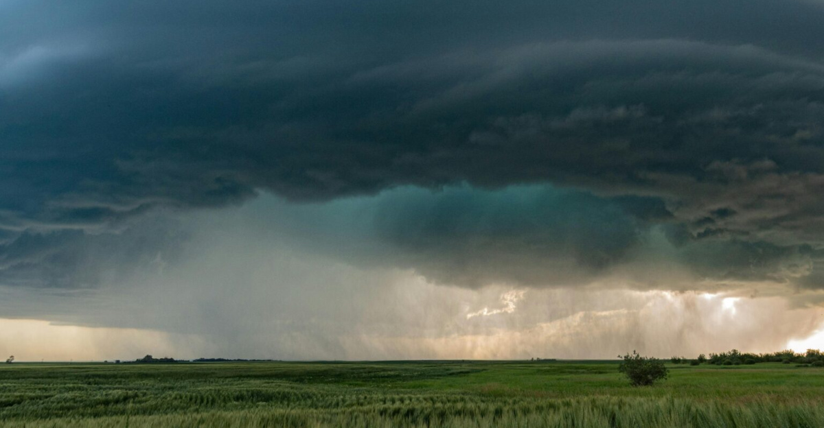 A powerful supercell storm looms over lush green fields in Saskatchewan, Canada.