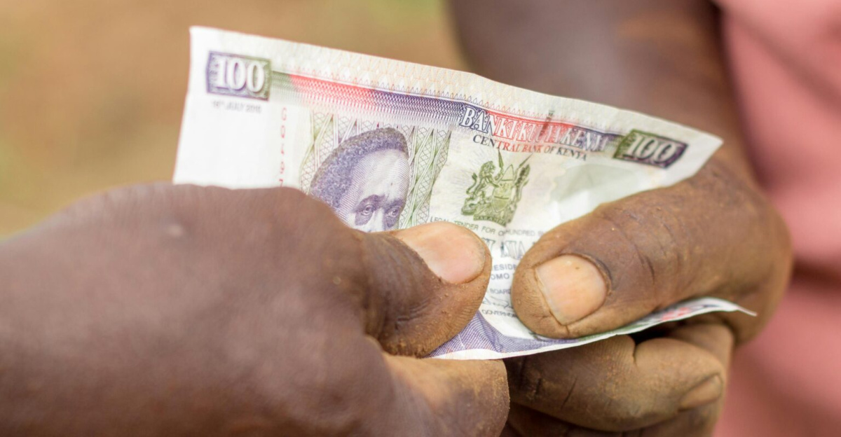 Captured moment of two individuals exchanging currency outdoors in Kenya.