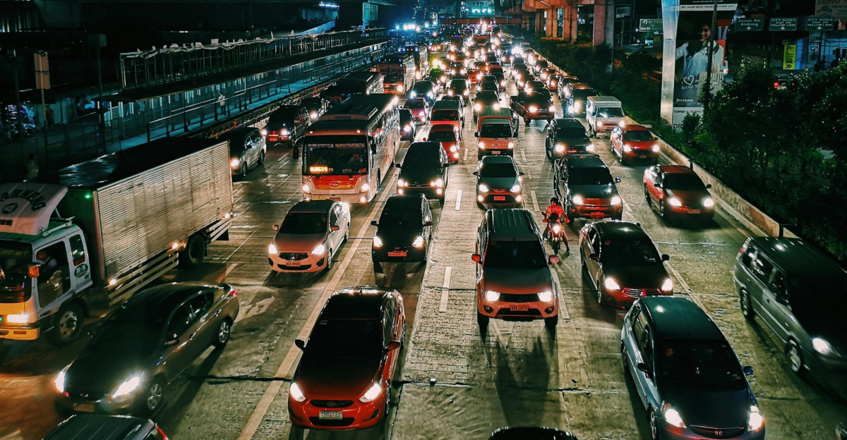 A bustling urban highway filled with cars and buses at night, showcasing city life and transportation.