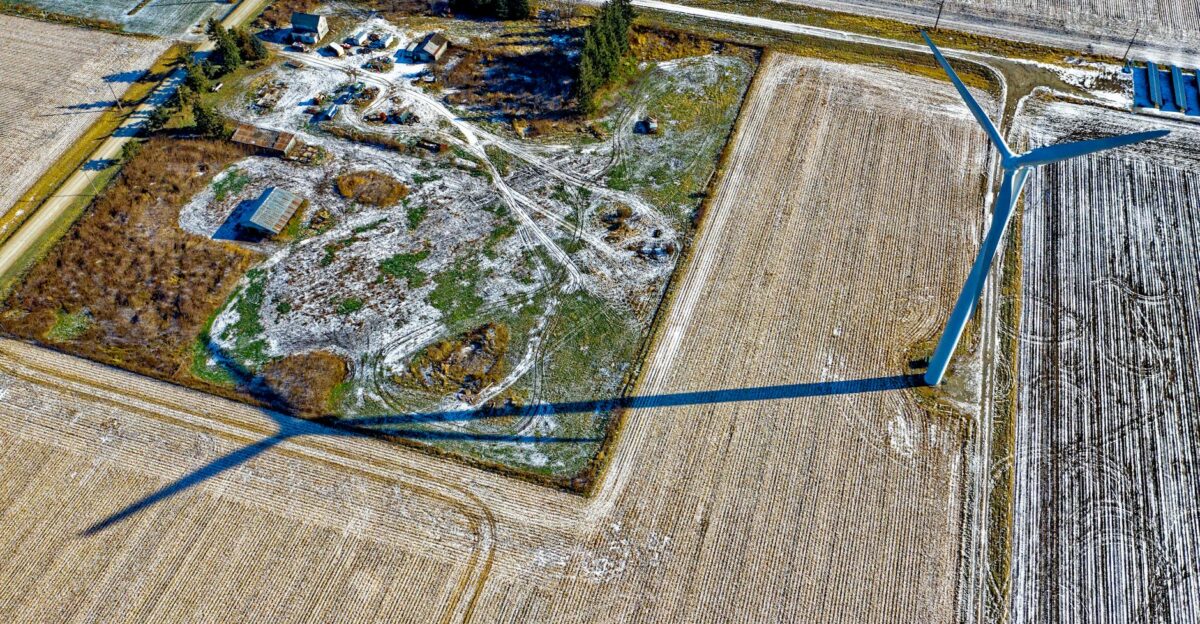 Aerial view of a wind turbine casting a shadow over fields in wintry Minnesota