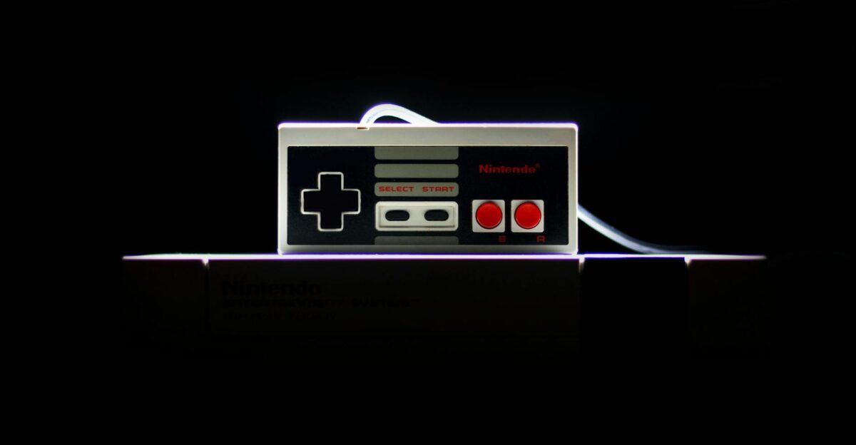 A close-up of a classic NES controller with dramatic lighting on a black background evoking nostalgia