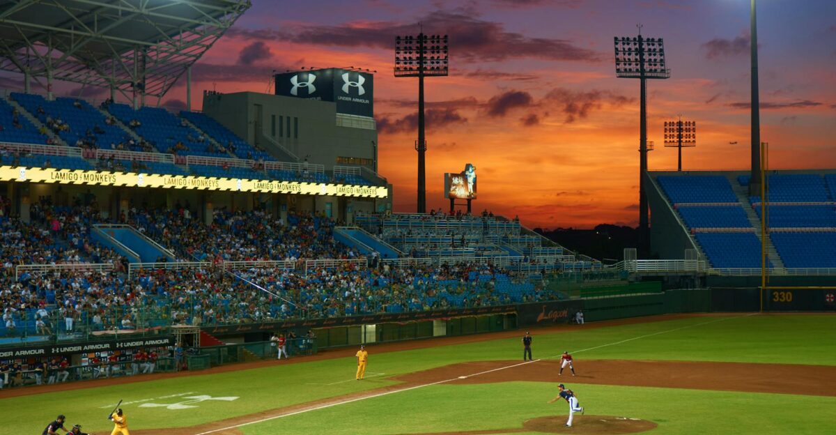 A vibrant baseball match in progress under stunning sunset skies in a crowded stadium