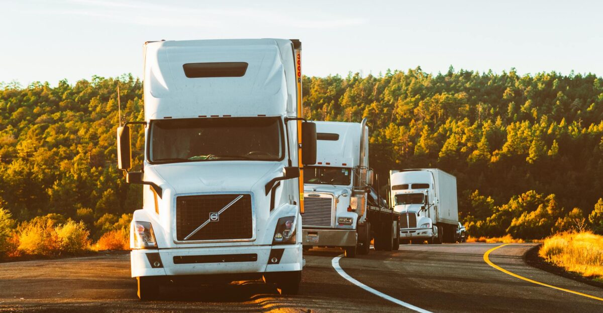 Three semi trucks driving on a highway through a forested landscape in Arizona