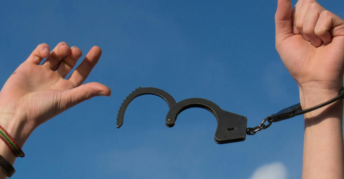 Symbolic image of freedom with open handcuffs against a bright blue sky.