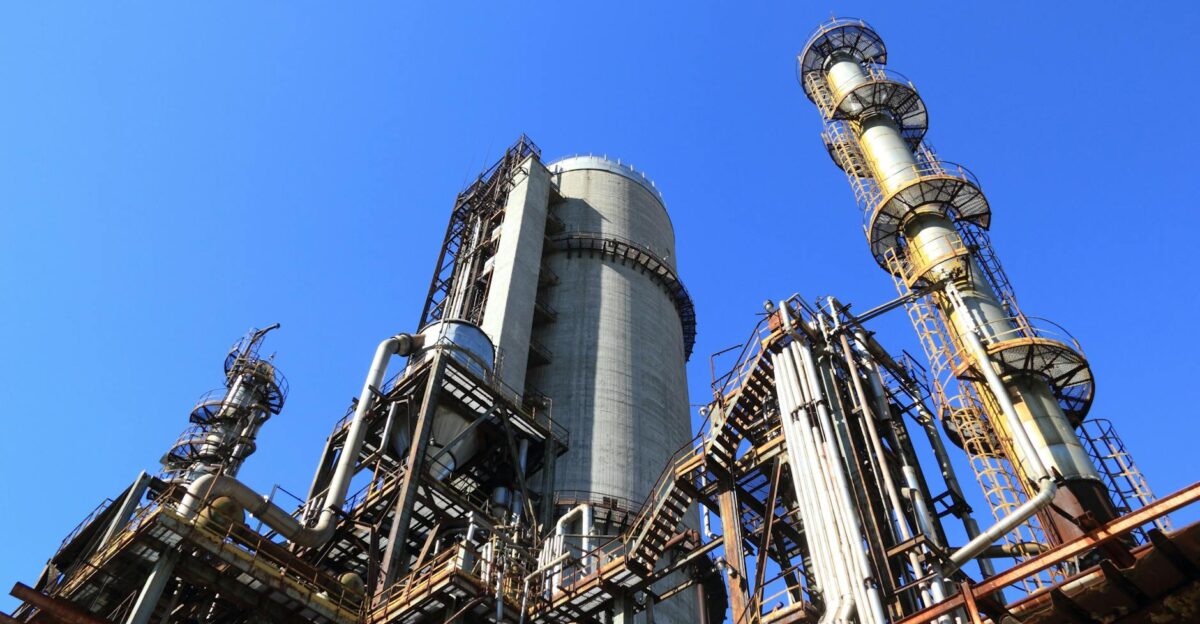 A towering industrial plant under a vivid blue sky showcasing its intricate architecture and industrial prowess
