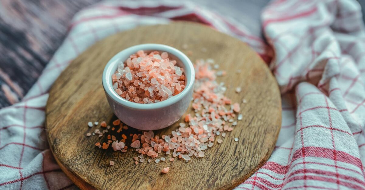 A close-up shot of pink Himalayan salt in a ceramic cup on a wooden board Ideal for culinary and health visuals