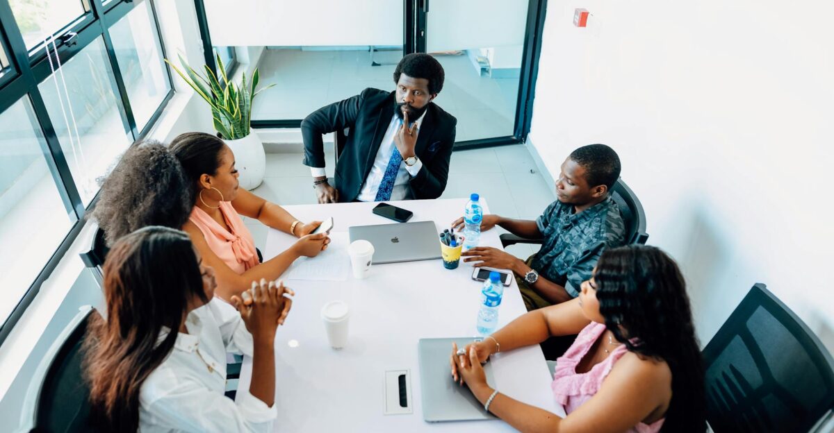 A group of professionals engaged in a business discussion around a table in a Lagos office