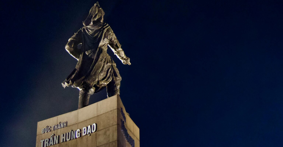 Dramatic night view of the Tran Hung Dao statue against a deep blue sky in Vietnam.