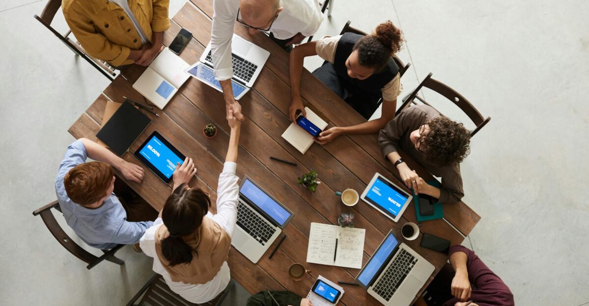 Top view of a diverse team collaborating in an office setting with laptops and tablets promoting cooperation