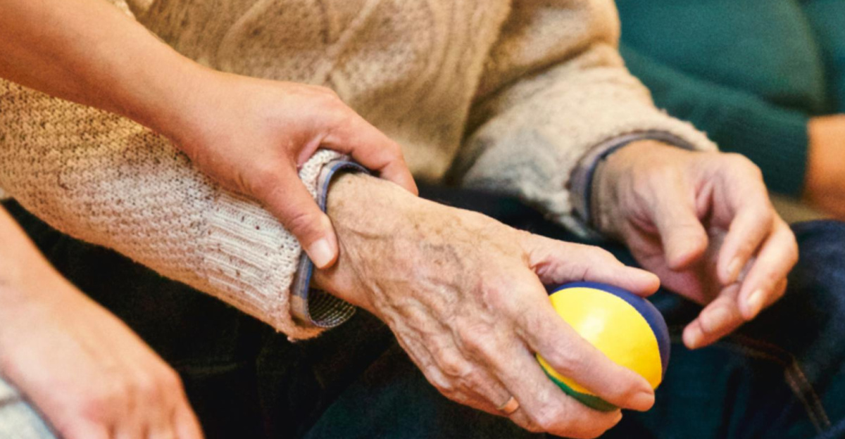 An elderly person receives support from a caregiver, holding hands indoors, showcasing compassion.