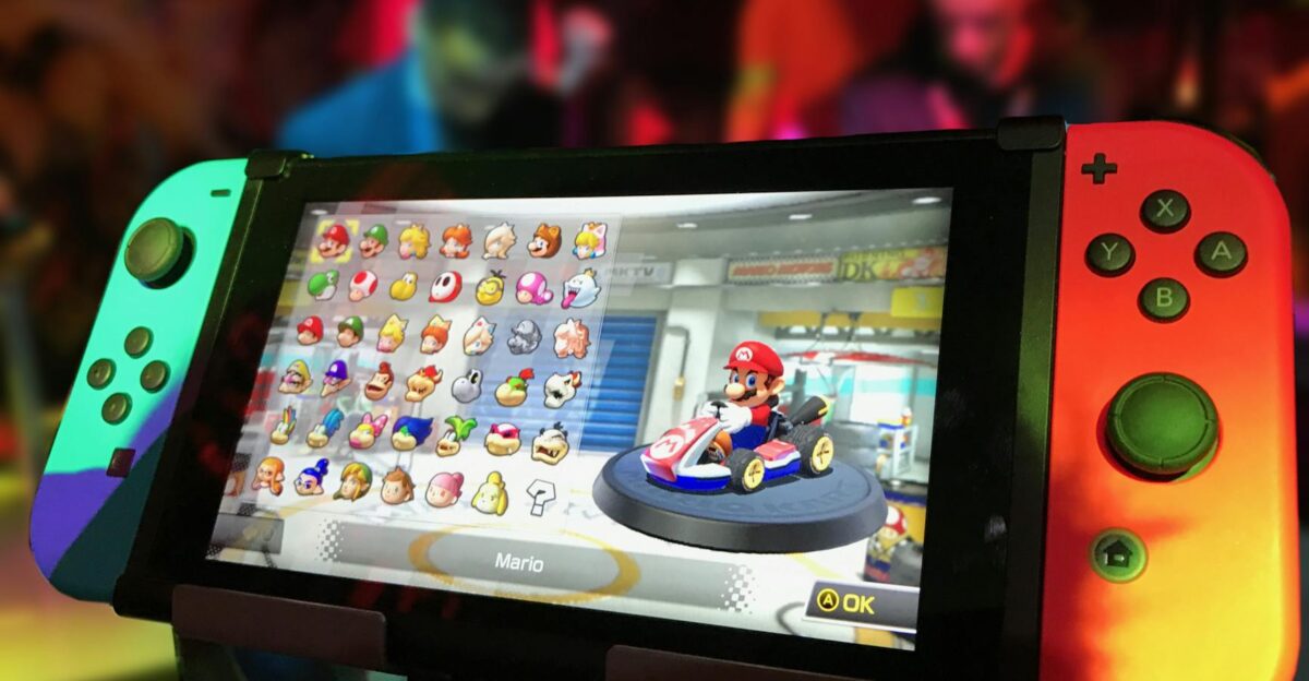 Close-up of a Nintendo Switch showing Mario Kart selection screen gaming atmosphere in the background