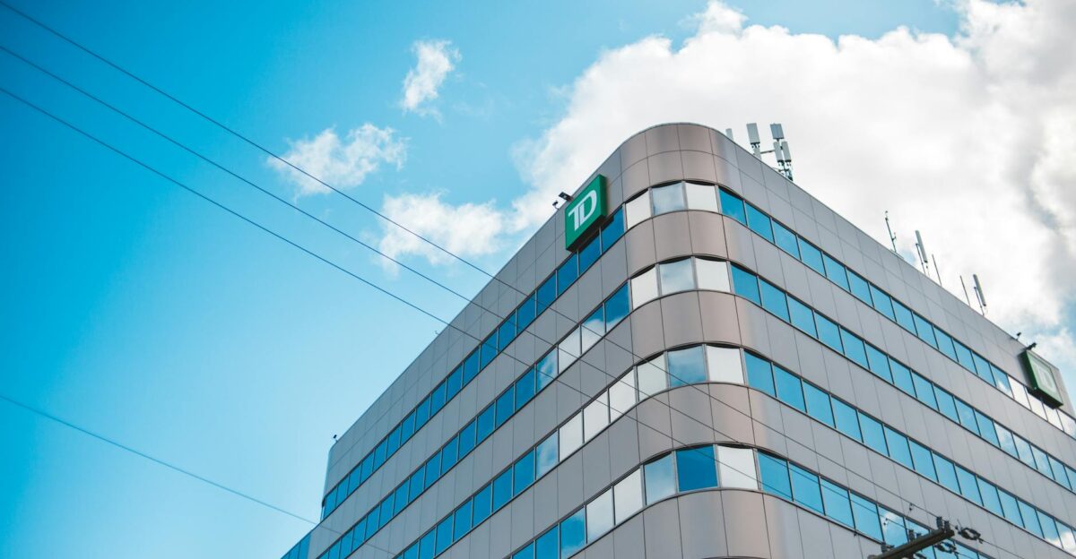 Low-angle shot of a modern skyscraper with glass windows set against a bright blue sky