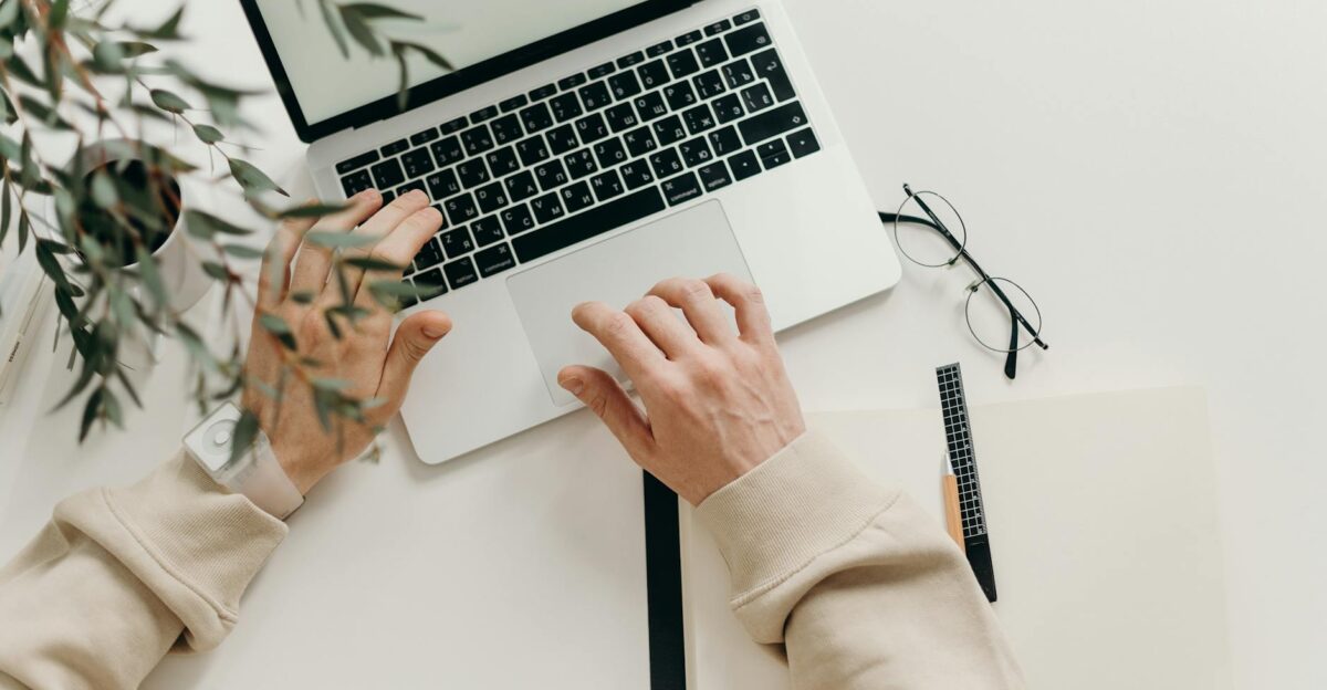 An overhead view of a person working on a laptop in a minimalist home office setting