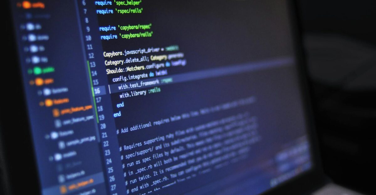 Close-up of a computer screen displaying programming code in a dark environment