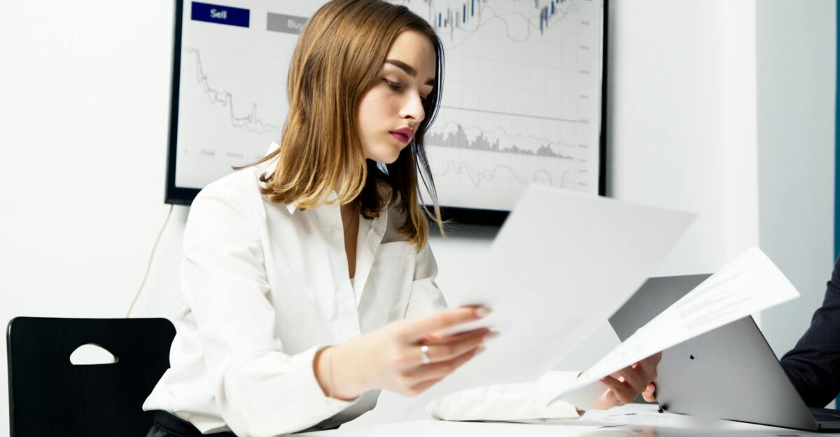 Focused woman analyzing financial reports in a modern office setting with charts and graphs