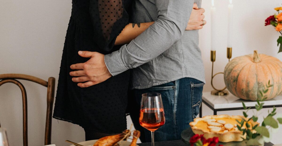 Couple embracing amidst a Thanksgiving feast with turkey and wine