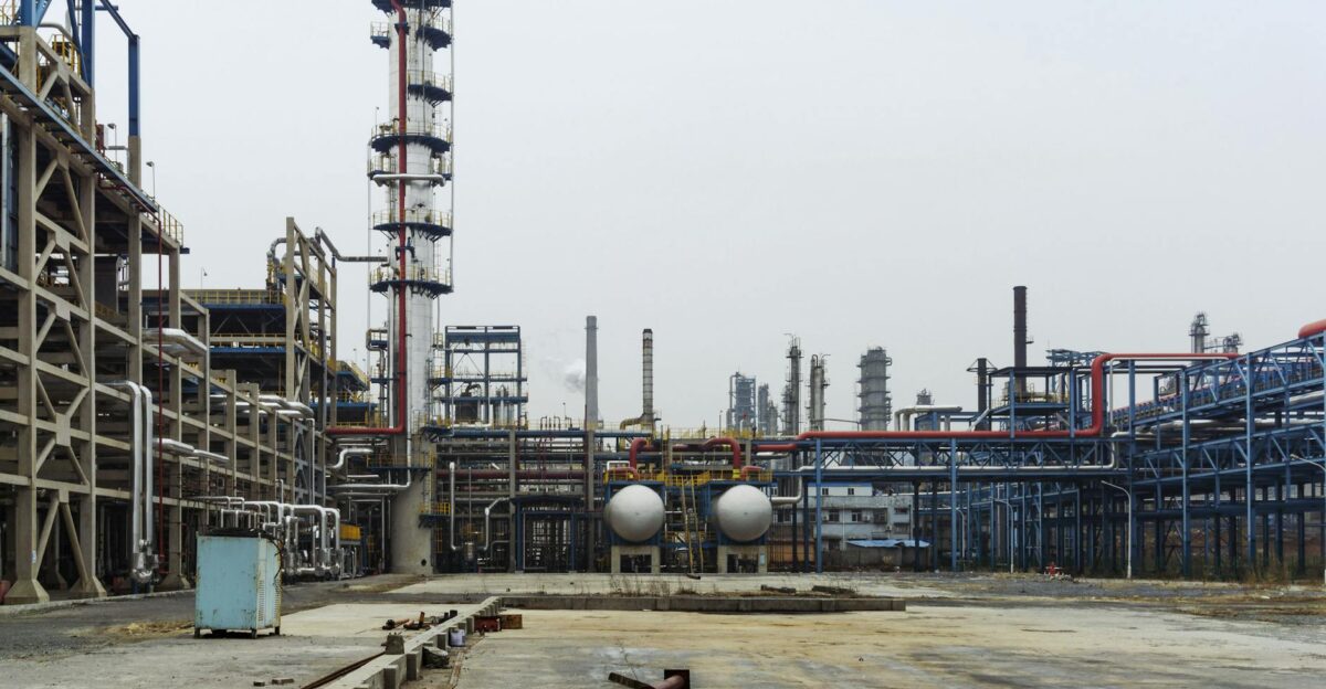 A detailed view of an industrial refinery featuring pipelines and large steel structures